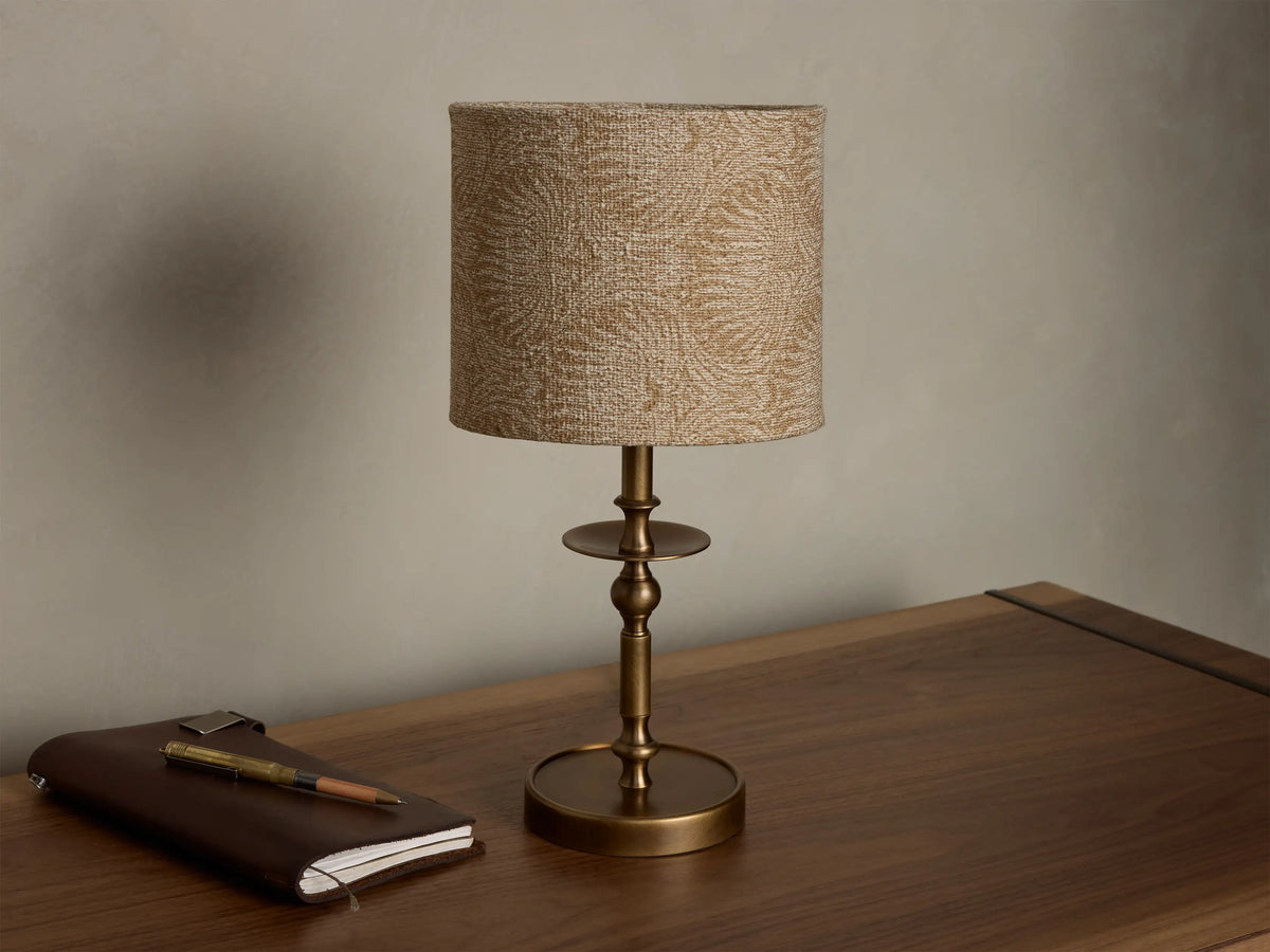 Front view of the Winslow Accent Table Lamp, featuring a patterned beige fabric shade and an antique brass base.