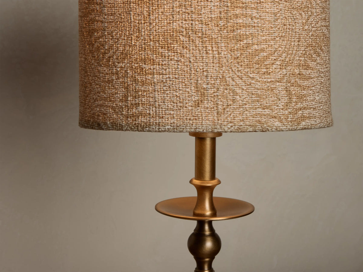 Close-up of the Winslow Accent Table Lamp, featuring a textured beige fabric shade and an antique brass sculptural base.