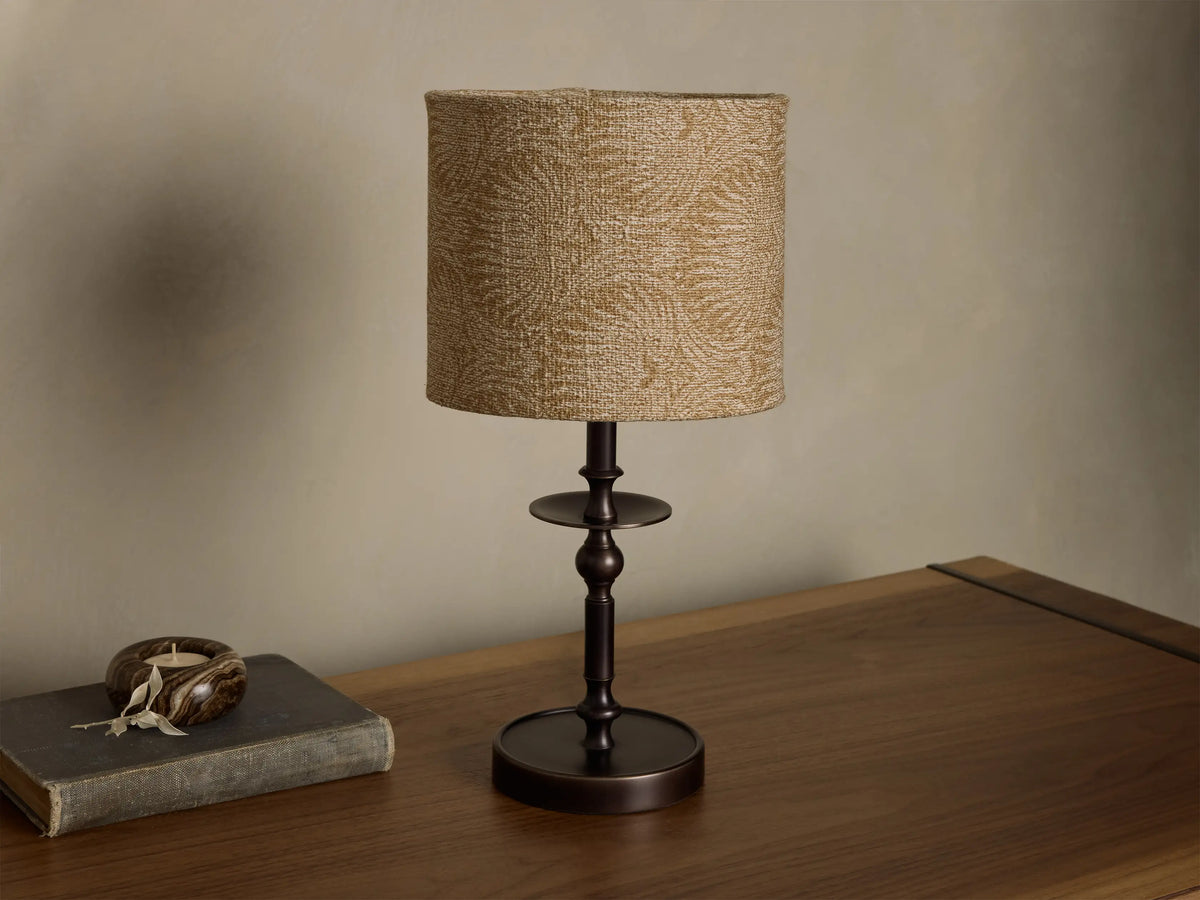 Front view of the Winslow Accent Table Lamp with an antique bronze iron base and a beige fabric shade with a subtle pattern.