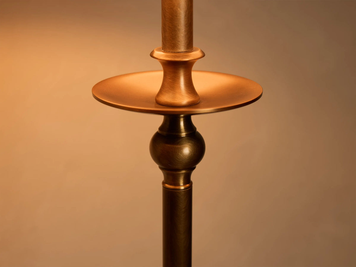 Front view of the Winslow Table Lamp with an antique brass finish base and a light brown patterned fabric shade, on a wooden table.