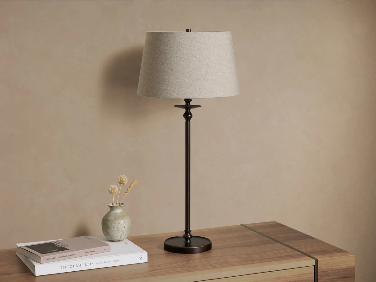 Close-up of the textured gray fabric shade and dark bronze-finished base of the Winslow Table Lamp, glowing with light.