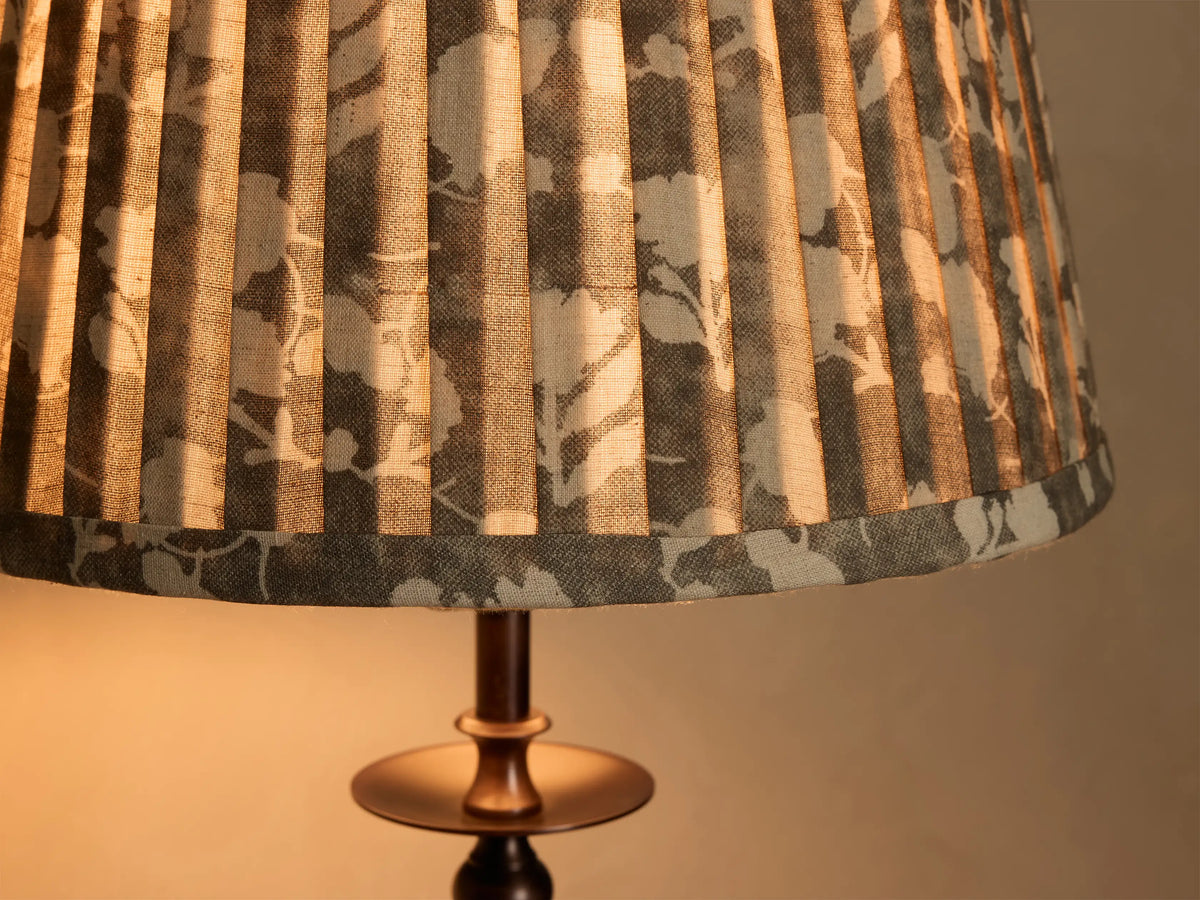 Close-up of the Winslow Table Lamp's pleated fabric shade with a light gray and dark gray floral pattern and antique brass base.