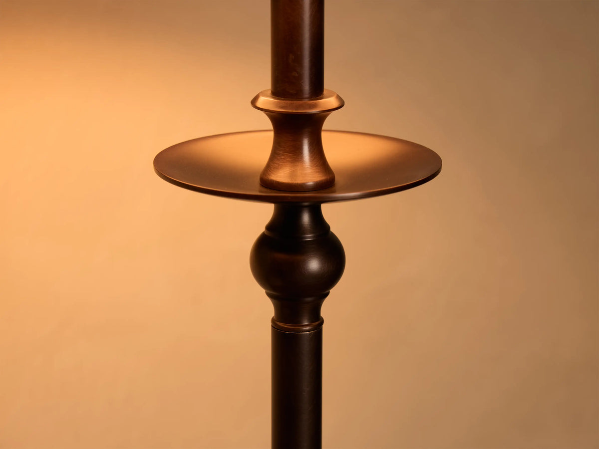 Close-up of the bronze-finished Winslow Table Lamp stem, showing a circular plate and turned details, illuminated.
