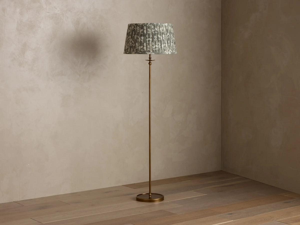 Front view of the Winslow Floor Lamp with an antique brass finish and a pleated muted green patterned fabric shade.