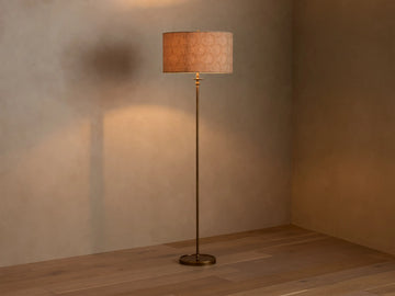 Full view of the Winslow Floor Lamp with antique brass finish and a textured light brown fabric shade, illuminating a room corner.