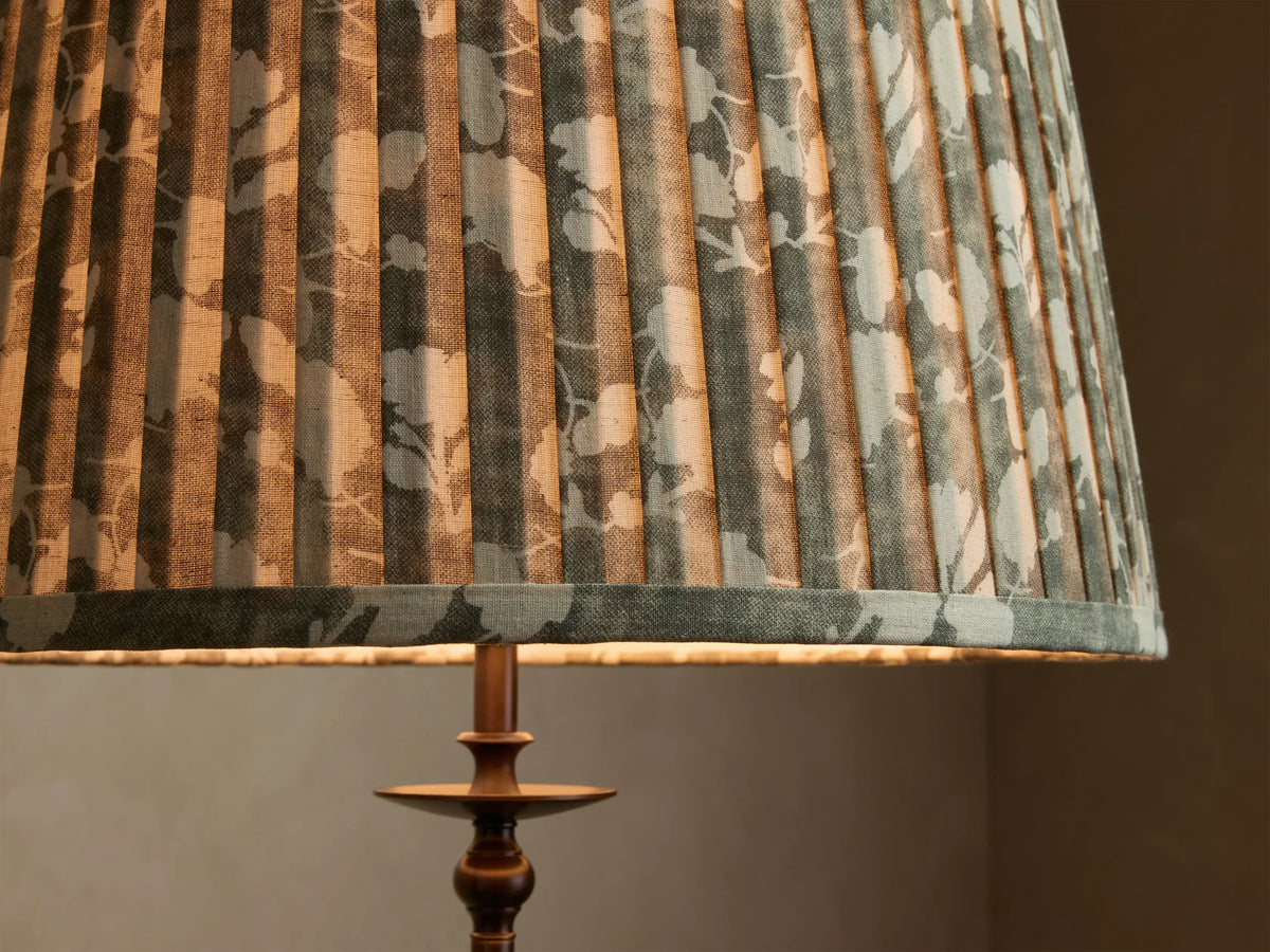 Close-up of the Winslow Floor Lamp, featuring a pleated grey-green fabric shade with white floral pattern, and an antique bronze base.