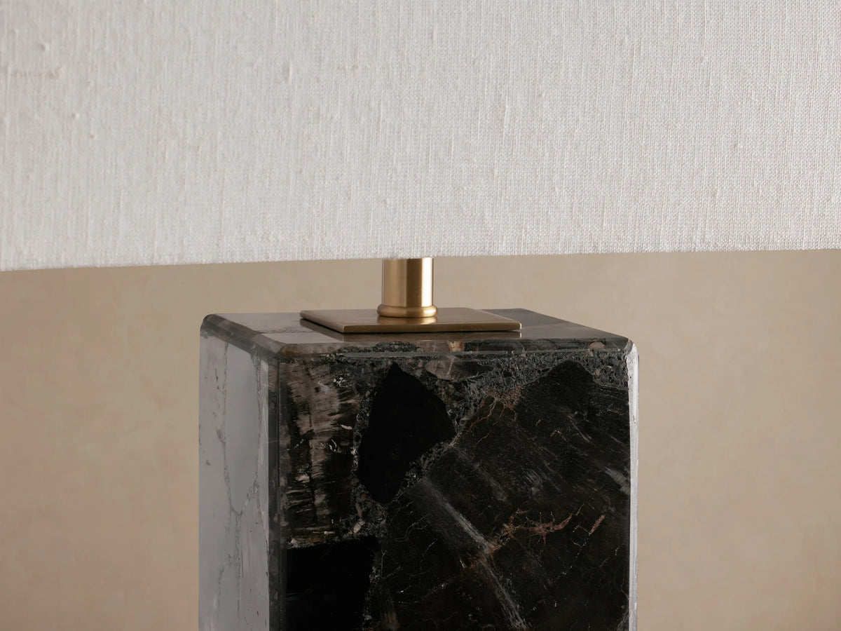 Oren Table Lamp close-up: dark, marbled stone cubic base, brass connector, and textured white linen shade.