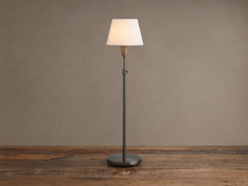 Upright pewter Candice Table Lamp with a creamy white conical shade, standing on a distressed wooden table against a warm neutral wall.
