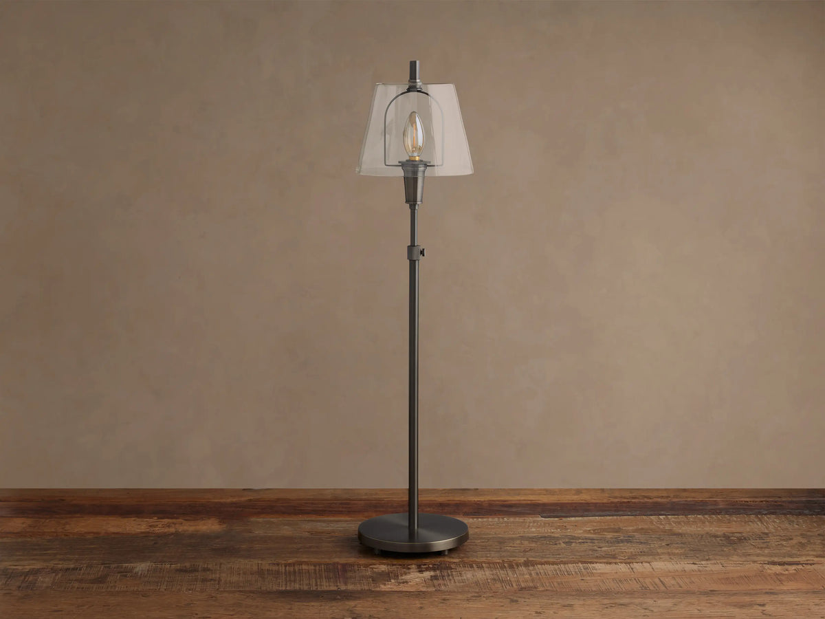 Tall Candice Table Lamp in pewter finish with a clear, angular glass shade and a visible filament bulb, on a rustic wood surface.