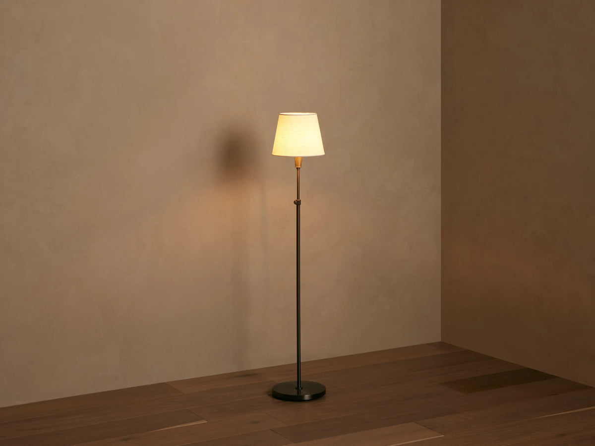 Close-up of Candice Floor Lamp: illuminated, tapered cream fabric shade over a brass-toned stem with a rotary switch.