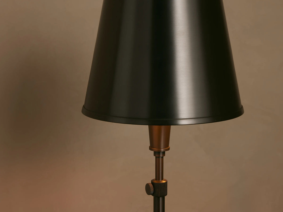 Dark pewter Candice Floor Lamp with a tapered shade and thin stand, on a wood floor against a light beige wall.