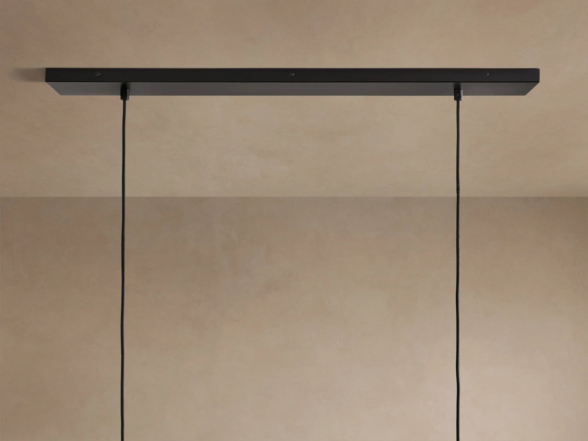 Lena Linear Chandelier close-up: dark, textured alder wood, glowing ochre interior, and reflective mirrored glass panel.