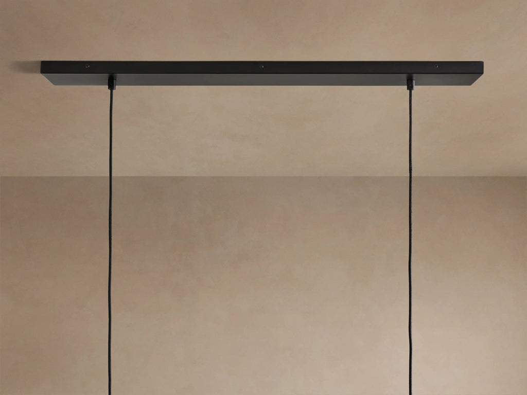 Lena Linear Chandelier close-up: dark, textured alder wood, glowing ochre interior, and reflective mirrored glass panel.