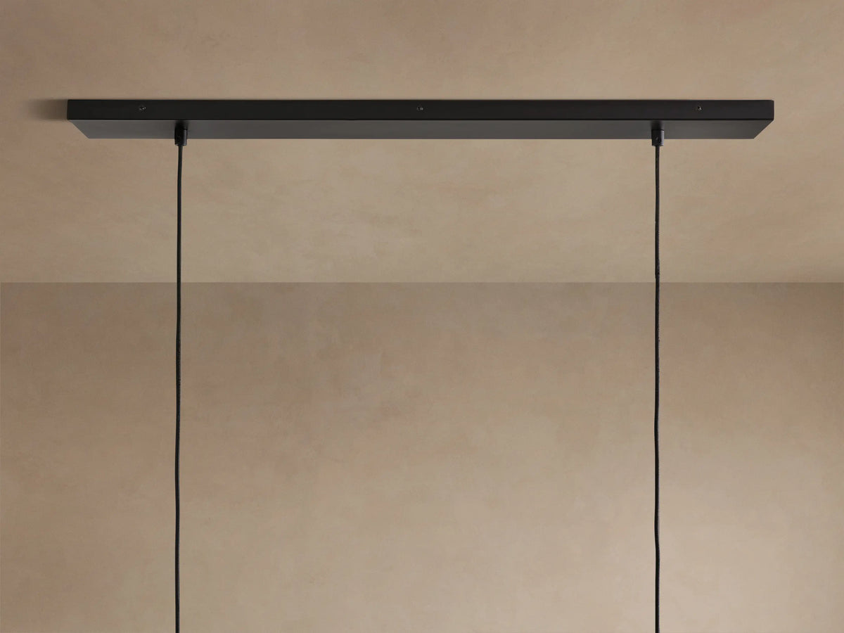 Close-up of Lena Linear Chandelier: dark textured alder wood top, ochre-finished interior, and mirrored glass panel.