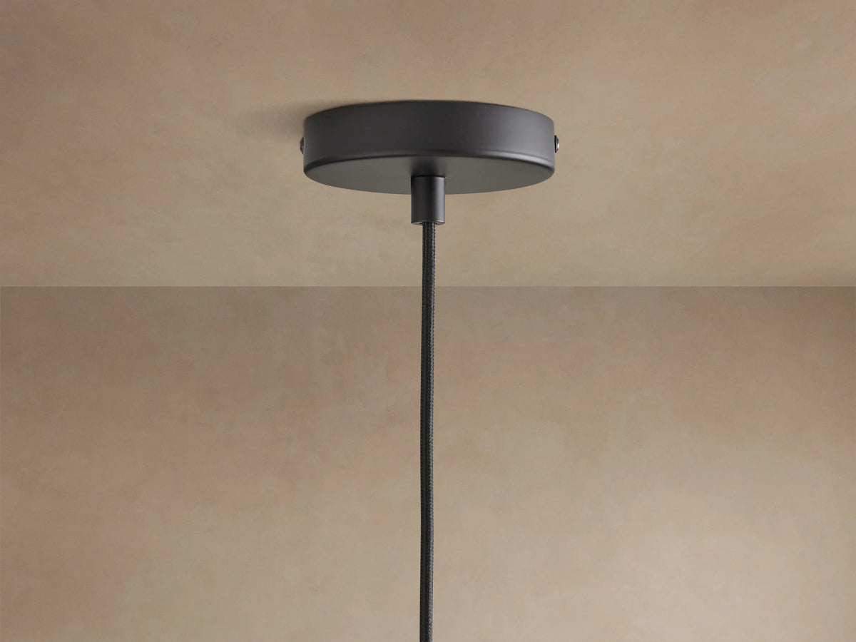 Dedalo Pendant: cylindrical milpa wood light with light ochre finish, natural grain, and a visible crack, hanging from a black cord.