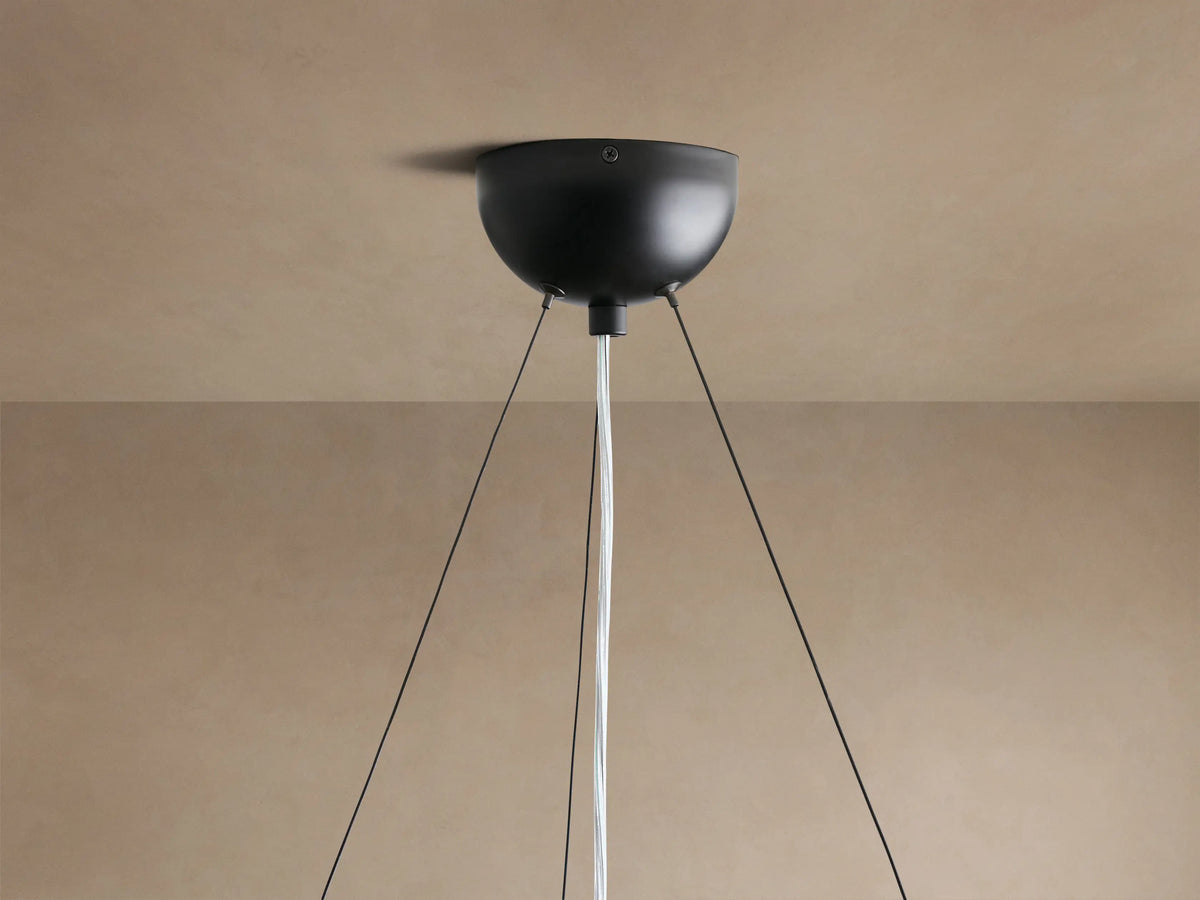 Close-up of Arruga Chandelier's organic, reddish-brown milpa wood dome with natural textures, and an illuminated bulb.