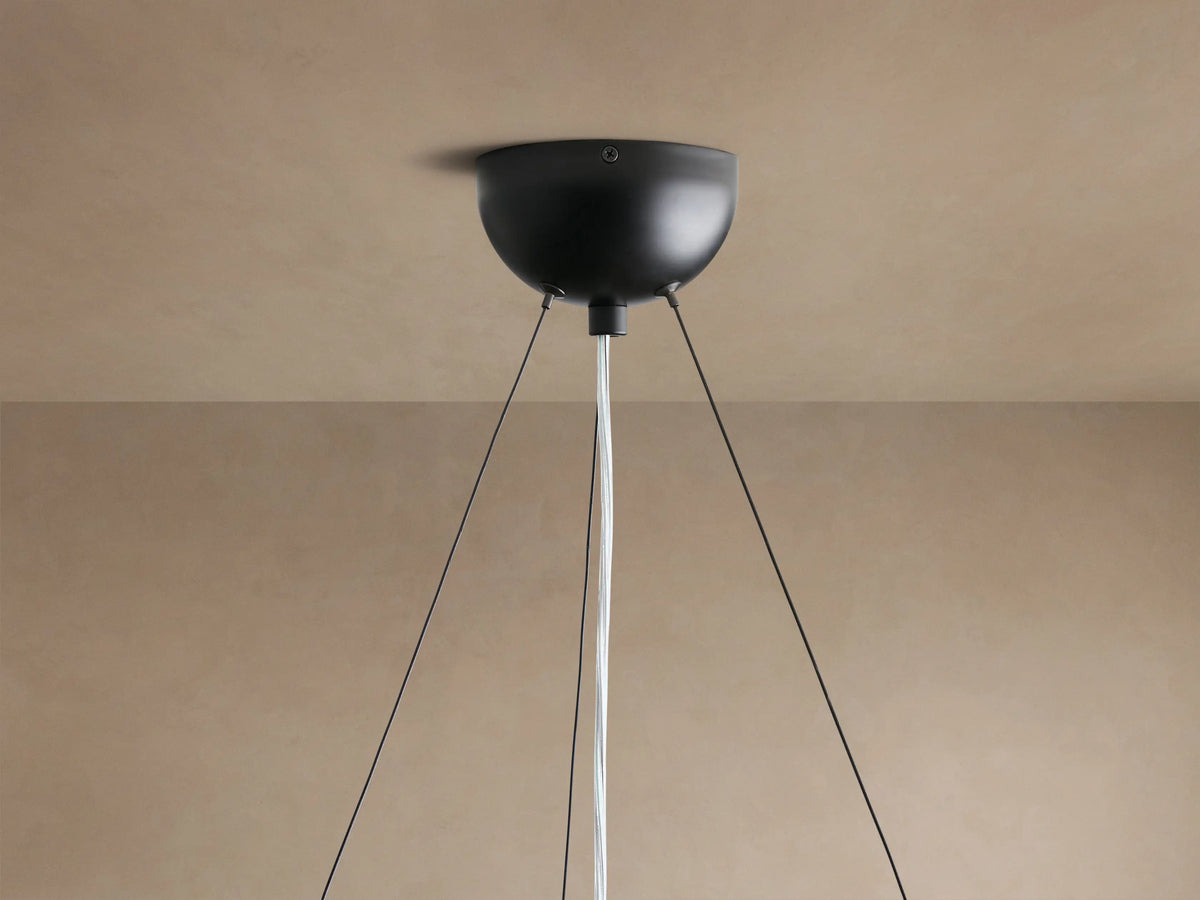 Arruga Chandelier, view from below. Dome of natural milpa wood with rich brown grain. Single globe bulb, silvered at bottom, glowing warm.