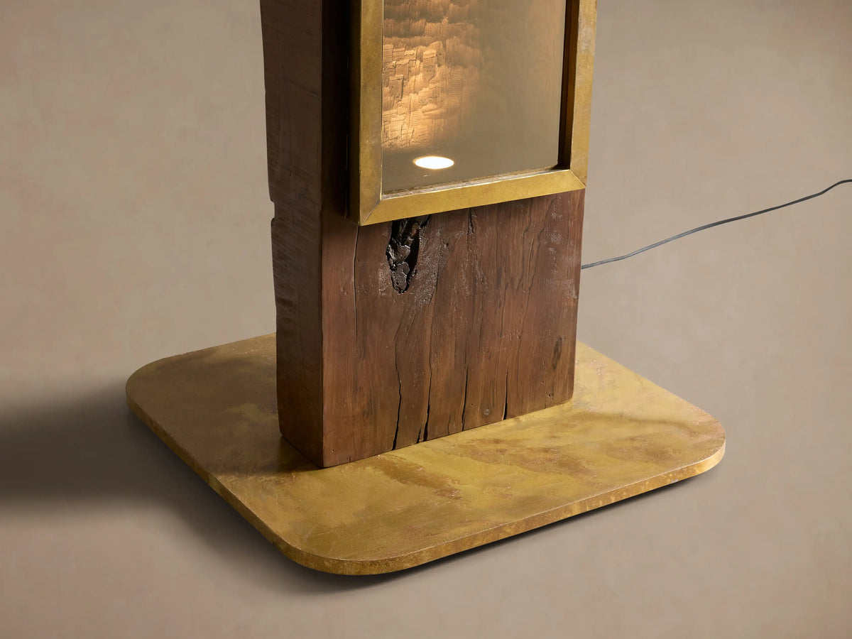 Vigas Floor Lamp: Tall, dark wood frame, central vertical mirrored panel with brass trim and base, on a wooden floor.