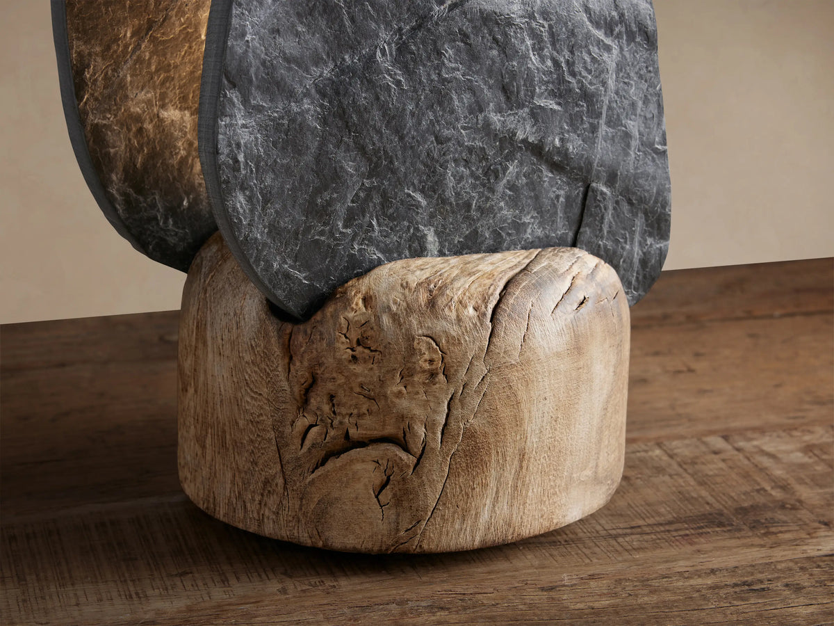 Shinto Table Lamp with dark grey textured slate rising from a rounded natural Melina wood base, on a wooden table.