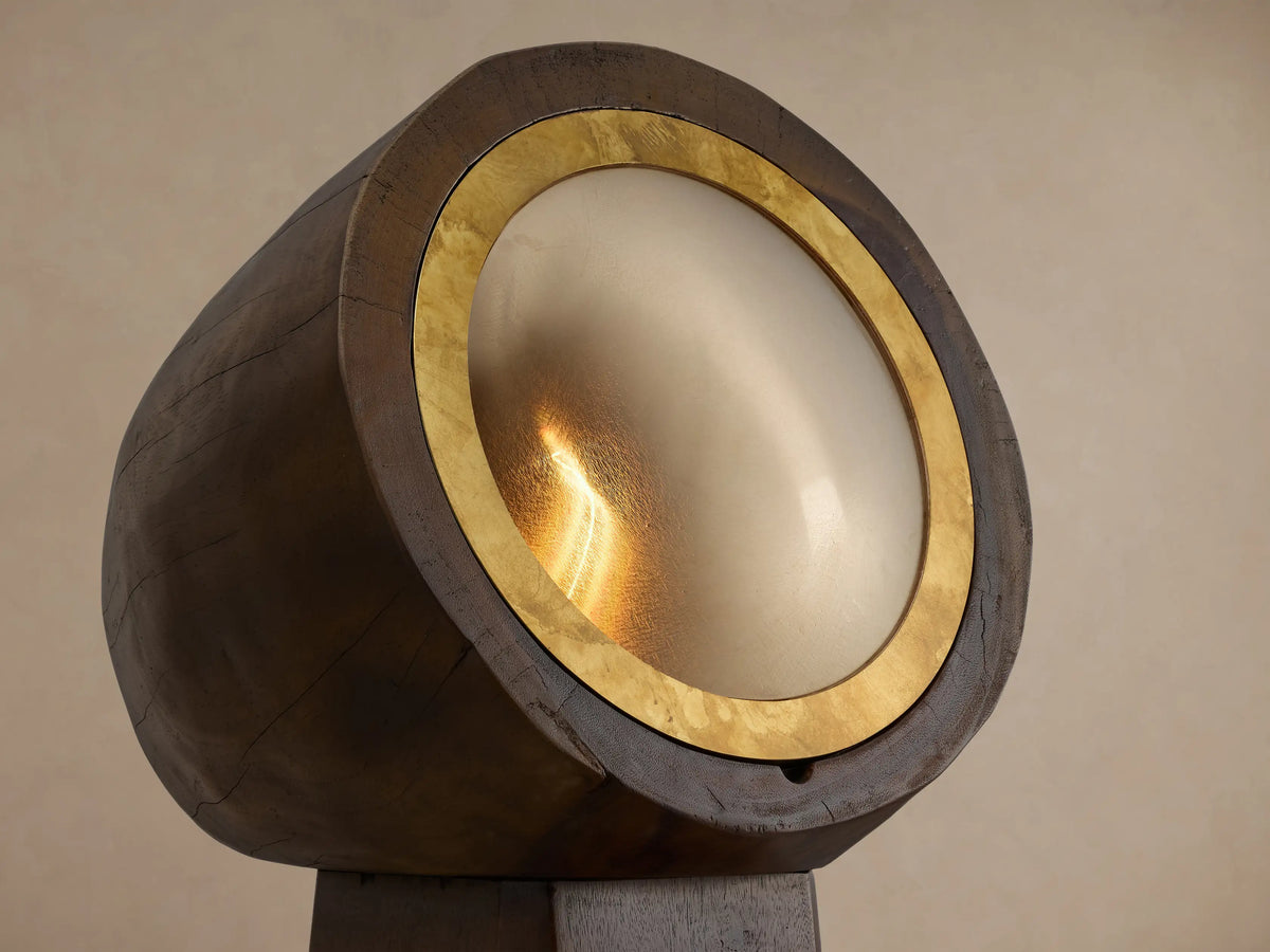 Agustin Floor Lamp: Dark faceted wood base, cylindrical top, with round opaque glass light framed by a golden ochre ring.