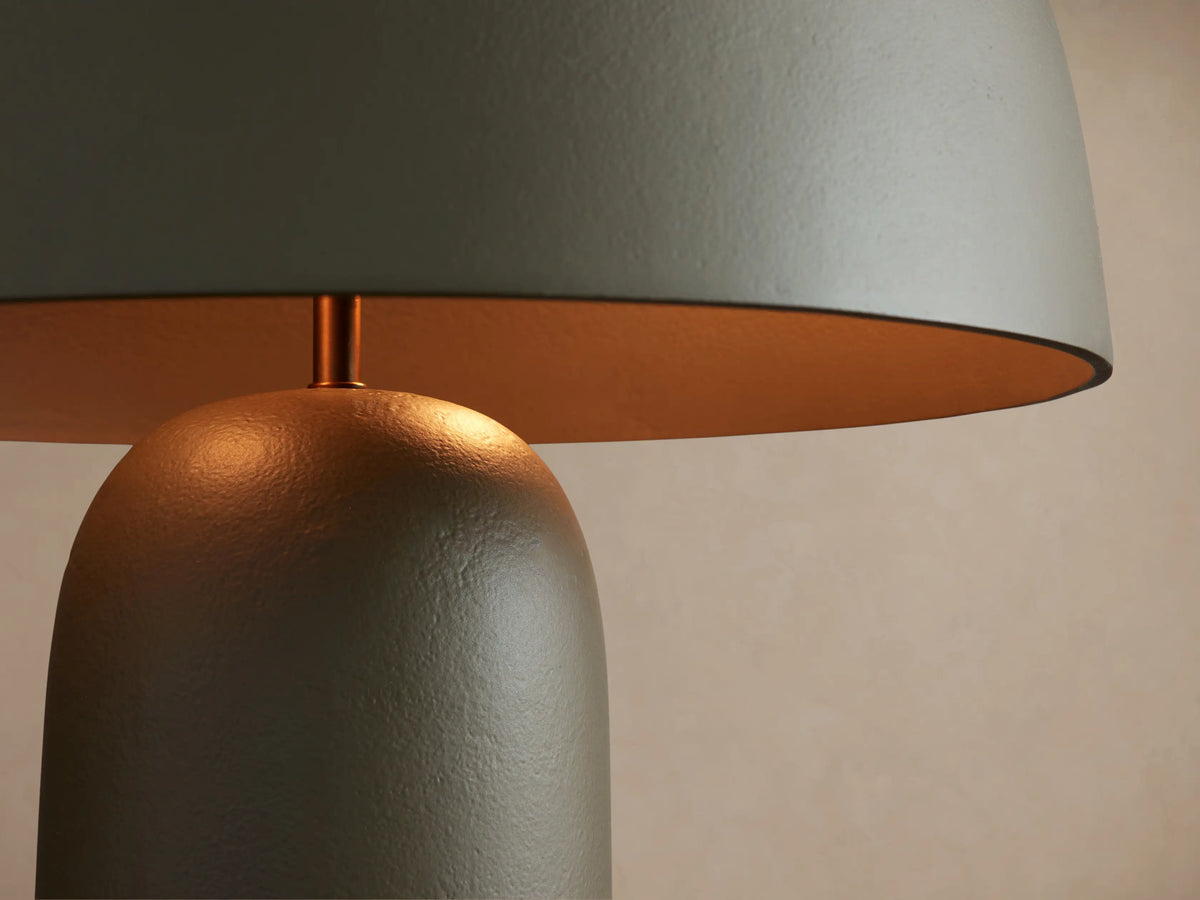Ira Table Lamp, olive green powder-coated cast aluminum, mushroom-shaped shade, cylindrical base, brass accent, on wood.