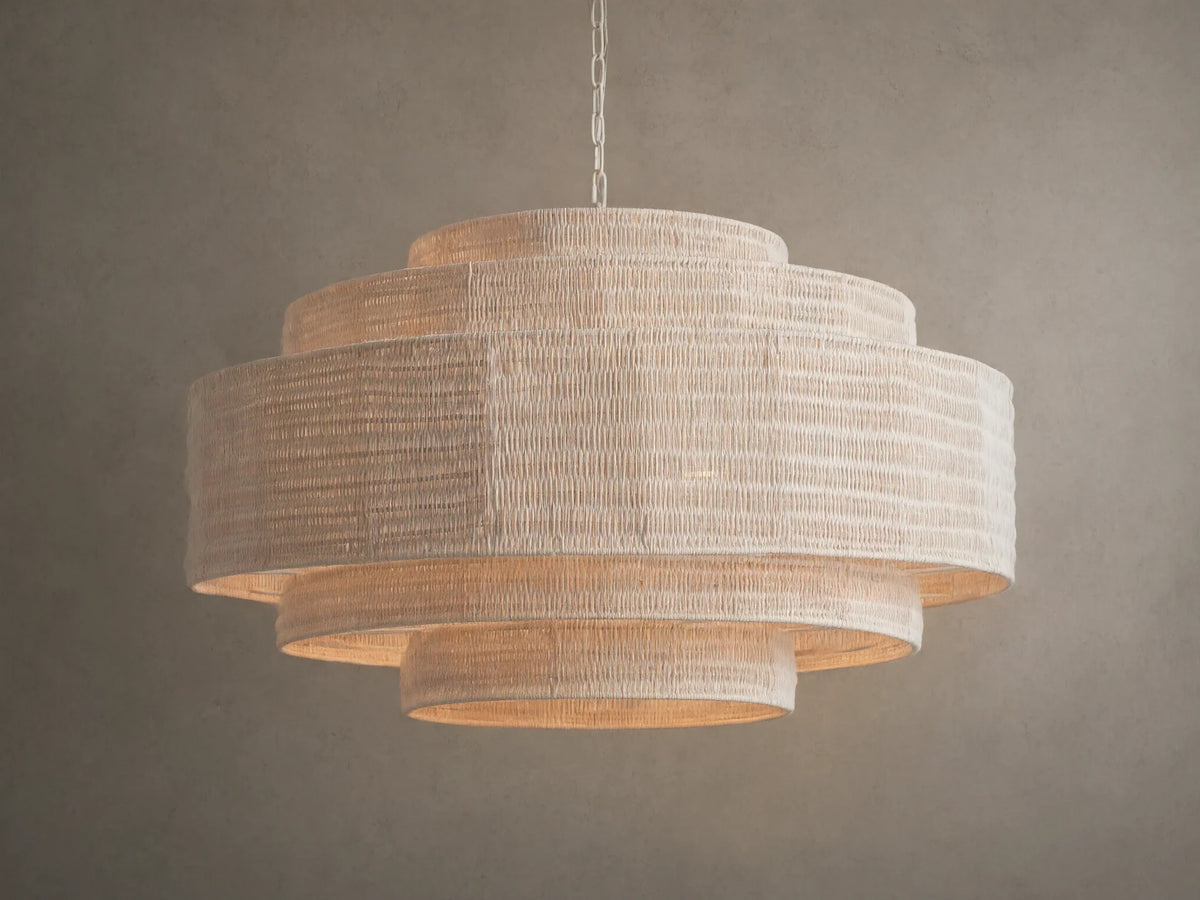 Paloma Chandelier with layered handwoven rattan shade in soft white, suspended from a chain against a gray background.