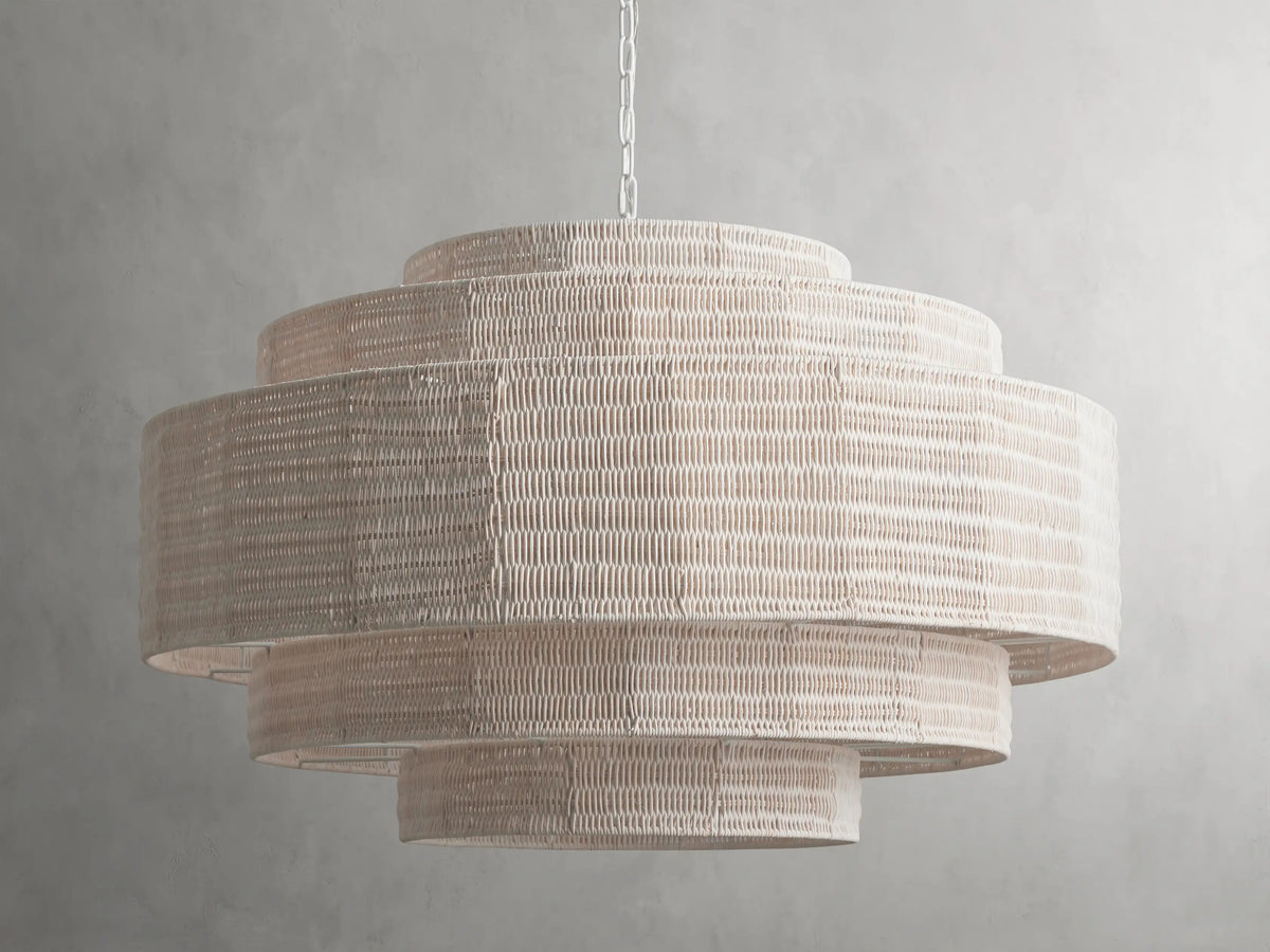 Paloma Chandelier with layered handwoven rattan shade in soft white, suspended from a chain against a gray background.