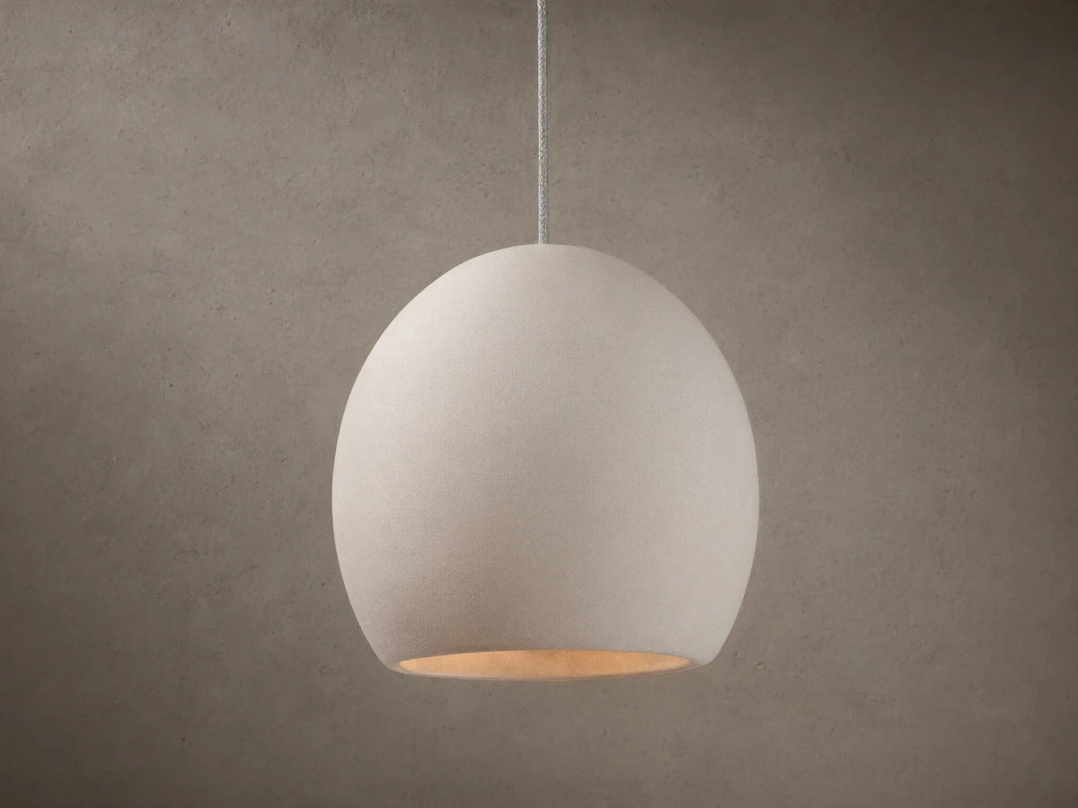 Arica Pendant with a spherical, light cream alabaster shade suspended from a thin cable, emitting a soft glow.