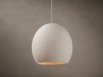 Arica Pendant with a spherical, light cream alabaster shade suspended from a thin cable, emitting a soft glow.