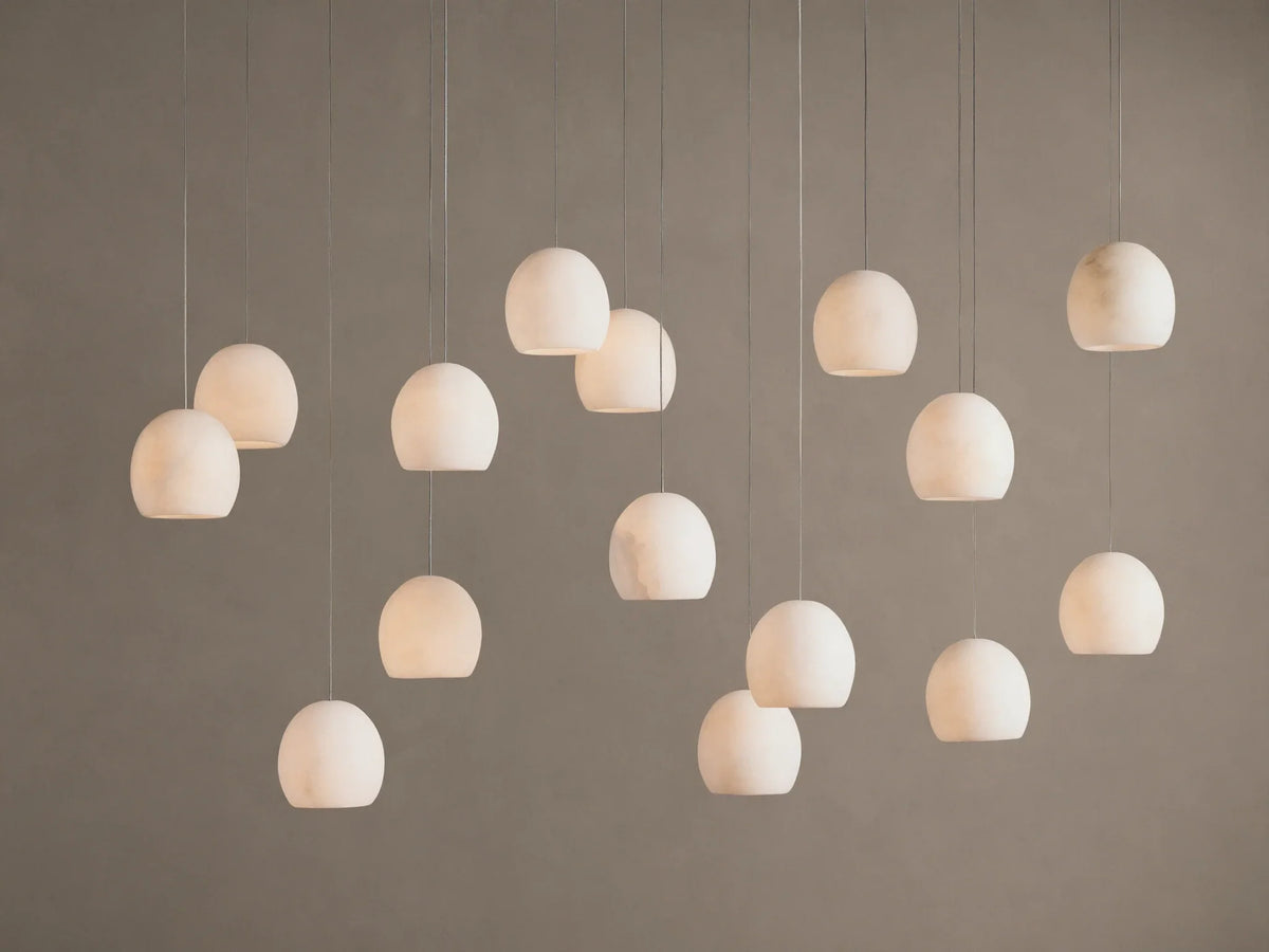 Arica Linear Chandelier with multiple glowing, spherical alabaster shades hanging at varying heights against a warm neutral wall.