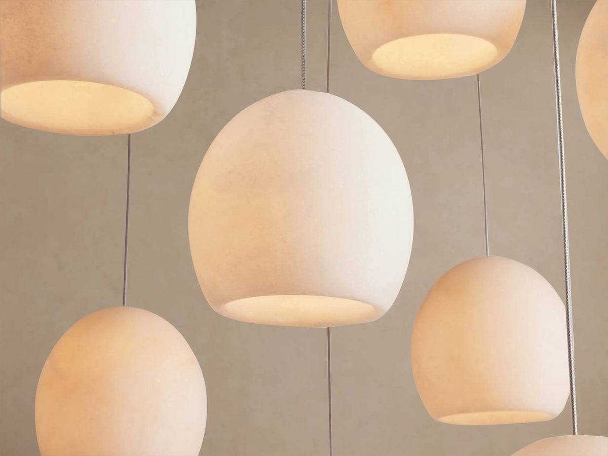 Arica Linear Chandelier with numerous spherical, natural alabaster shades suspended by thin silver cables at varying heights.