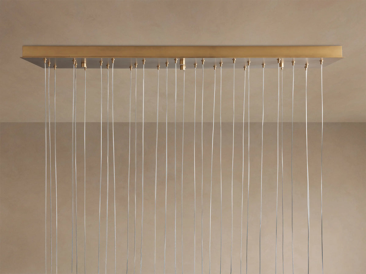 Arica Linear Chandelier close-up: multiple glowing, curved alabaster shades in light beige, suspended by thin cables.
