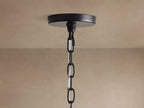 Close-up of Rosalind Rattan Chandelier in Black. Matte black iron frame, a rattan-wrapped arm, and a lit candelabra bulb.