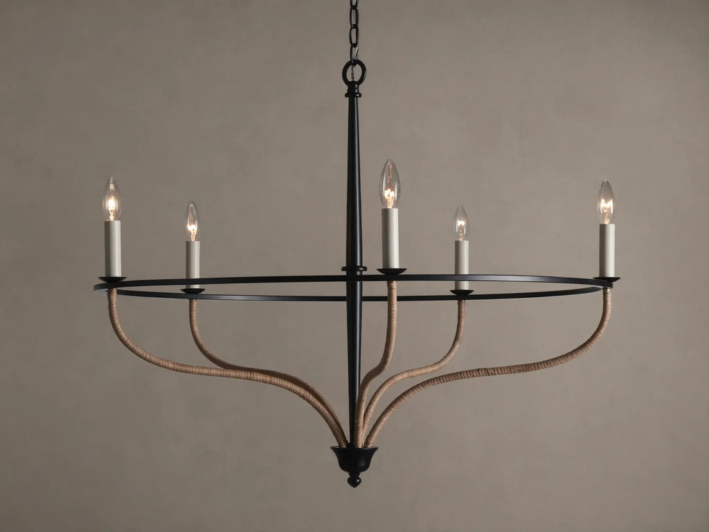Black iron Rosalind chandelier with five illuminated candle-like bulbs. Curved arms are wrapped in natural rattan.
