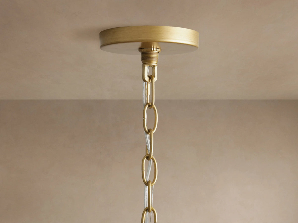 Rosalind Chandelier. Close-up of brass finish with elegant curved rods, a flat ring, and two glowing candelabra bulbs.