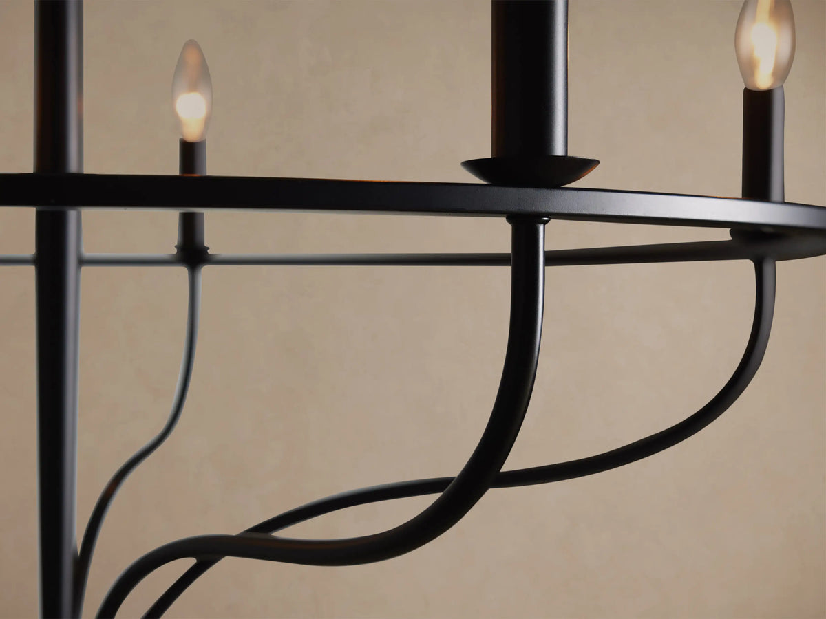 Matte black Rosalind Chandelier with five candelabra bulbs, circular frame, and curved arms, hanging against a light wall.