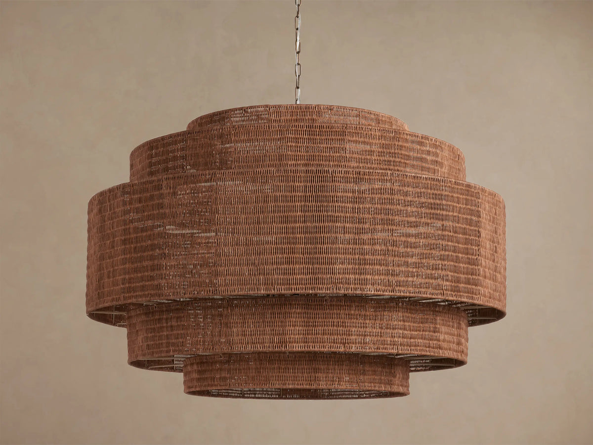 Paloma 52" tiered brown woven rattan chandelier hangs from a chain, with warm light glowing from within its shades.