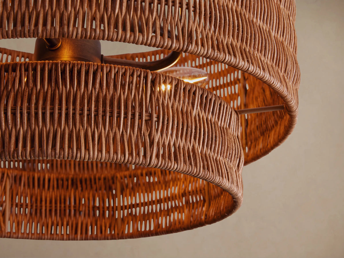Paloma Flush Mount with a tiered, handwoven light brown rattan shade mounted to a dark bronze ceiling plate on a beige ceiling.