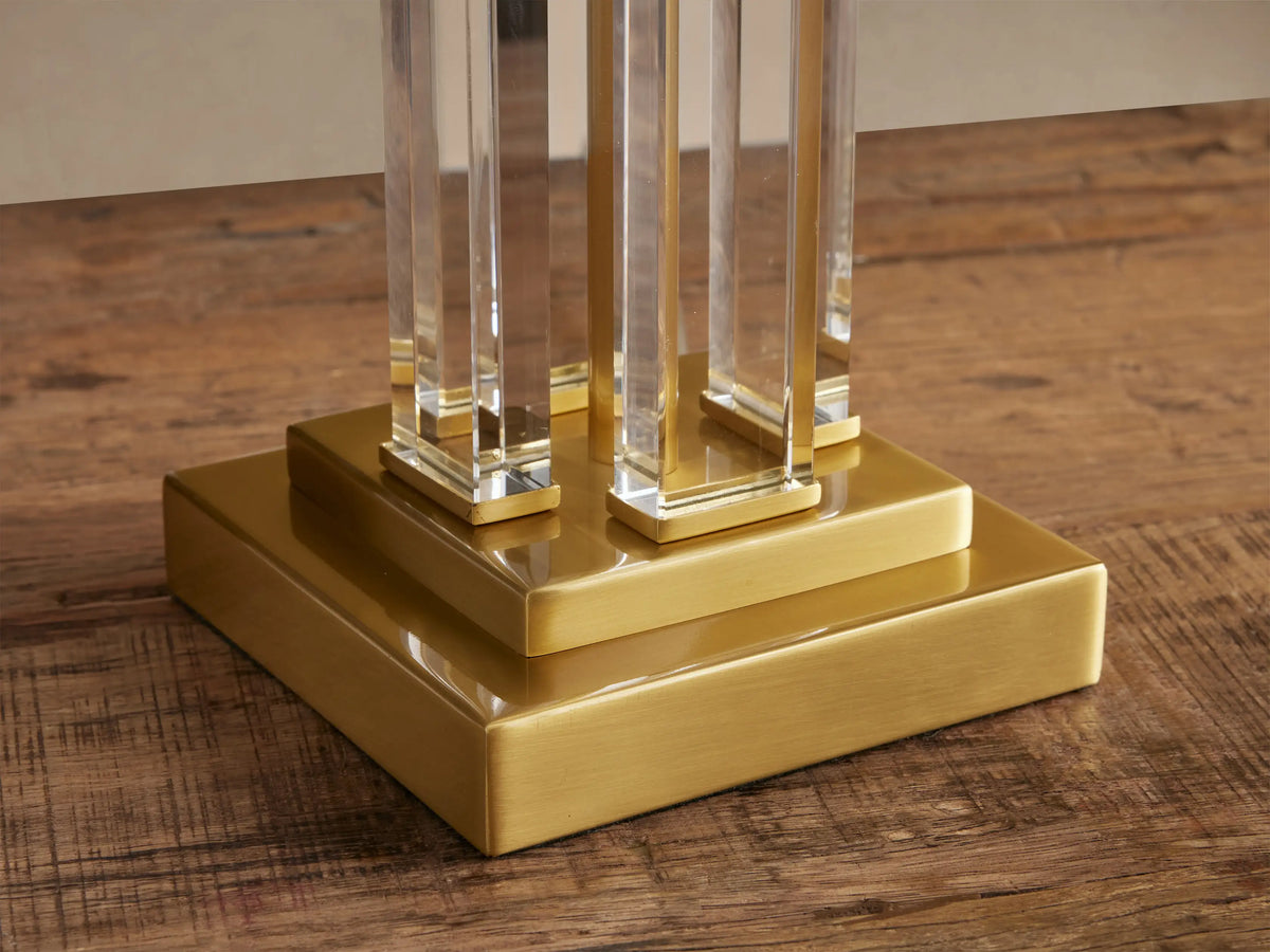 Dawson Table Lamp with rectangular white fabric shade, clear acrylic body, and polished brass base, on a wooden table.