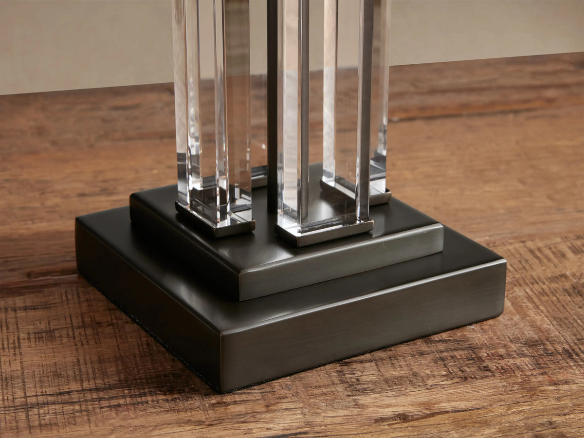 Dawson Table Lamp: white rectangular shade, dark metal base, stem with dark & clear vertical bars, on a wooden table.