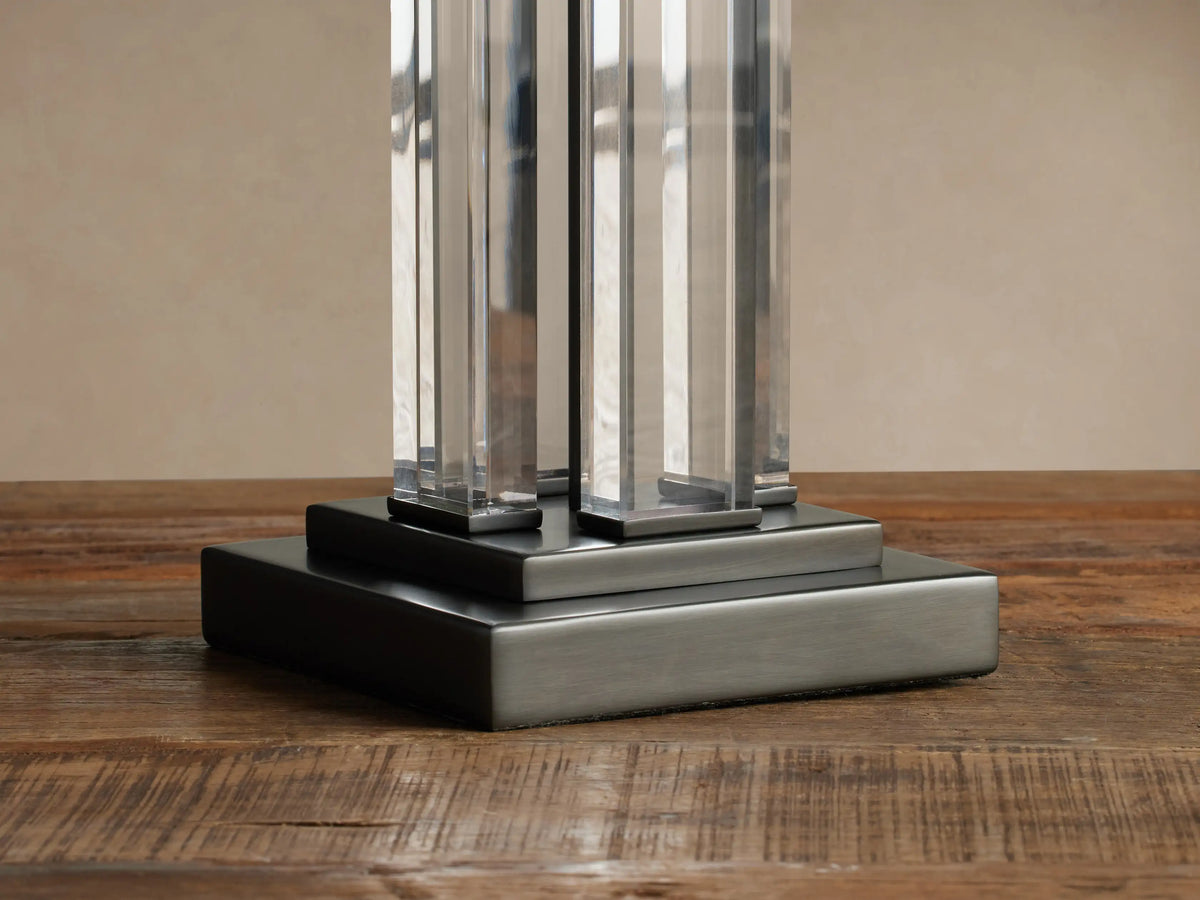 Dawson Table Lamp: rectangular cream shade, clear acrylic column stem with dark accents, resting on a rustic wood surface.