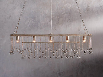Aubrey Rectangular Chandelier with a silver handcrafted iron frame, hanging Italian glass crystals, and five glowing bulbs.