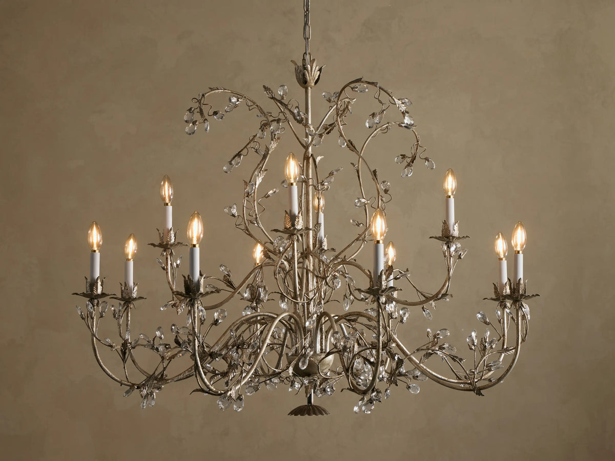 Claudette Chandelier: Ornate grey/silver-toned iron chandelier with 12 lit candle-style bulbs and numerous clear glass crystals.