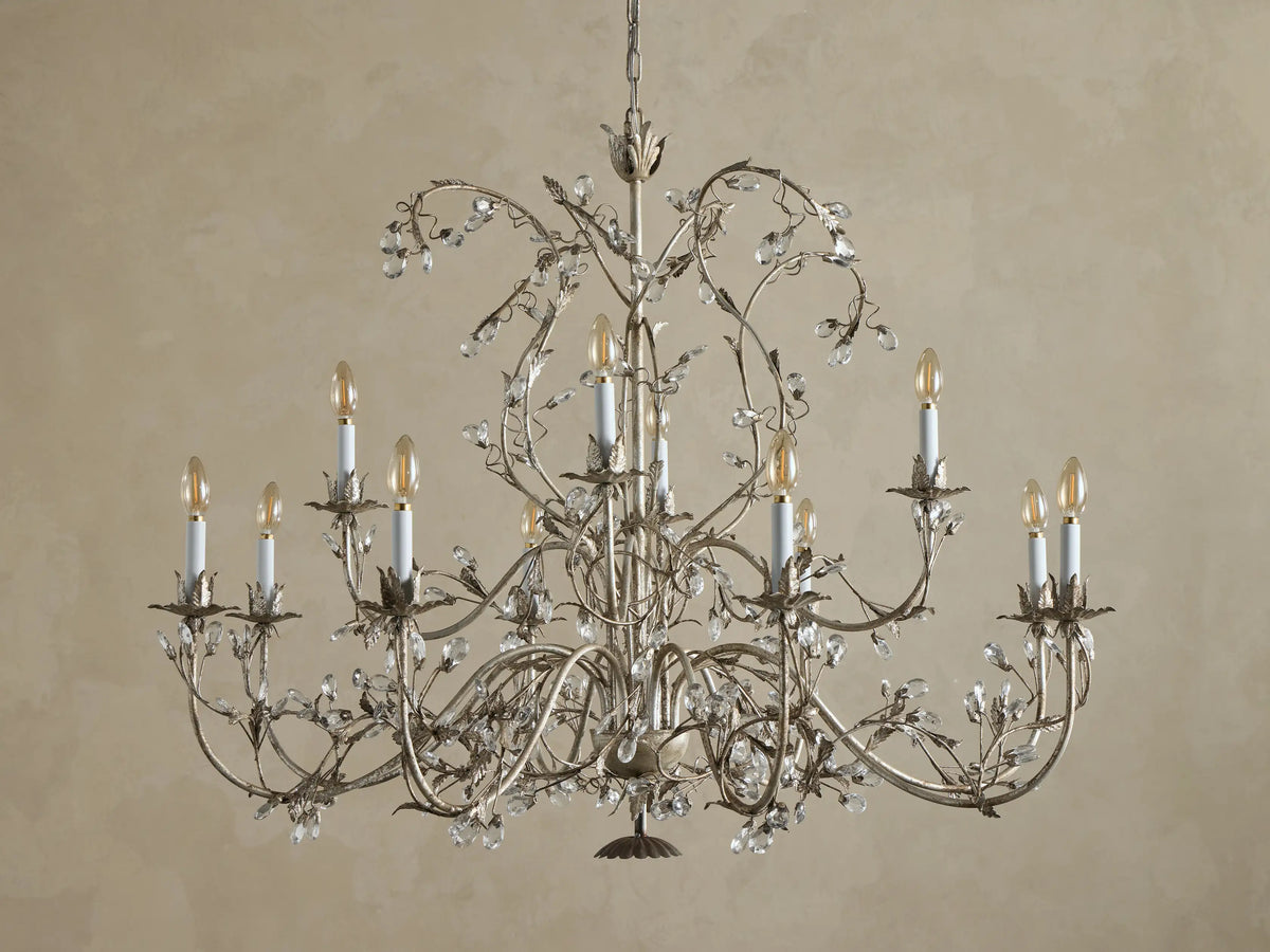 Claudette Chandelier: Ornate grey/silver-toned iron chandelier with 12 lit candle-style bulbs and numerous clear glass crystals.