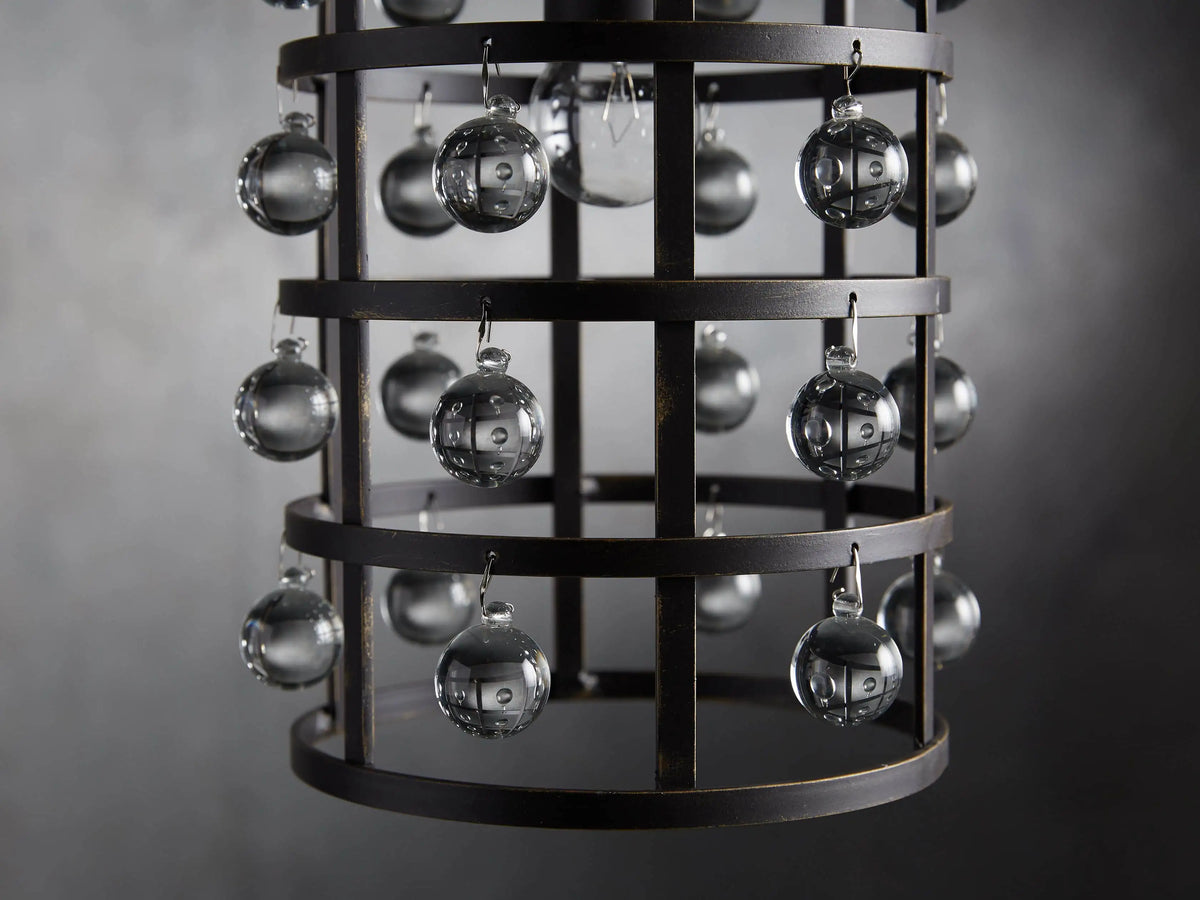 Iron cage pendant with antiqued metallic finish, adorned with Italian crystal spheres, hanging from a chain on a textured wall background.