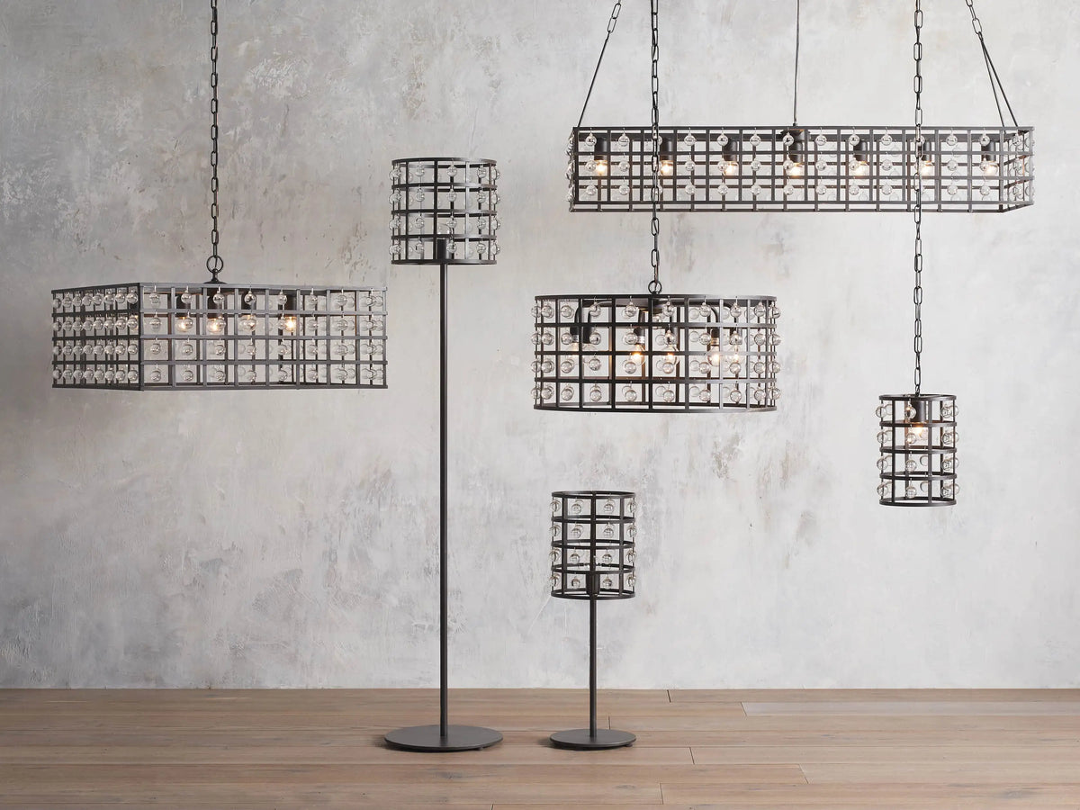 La Cage Pendant in bronze hangs in an elegant room, featuring a square iron cage frame with Italian crystal spheres, suspended from a long chain.