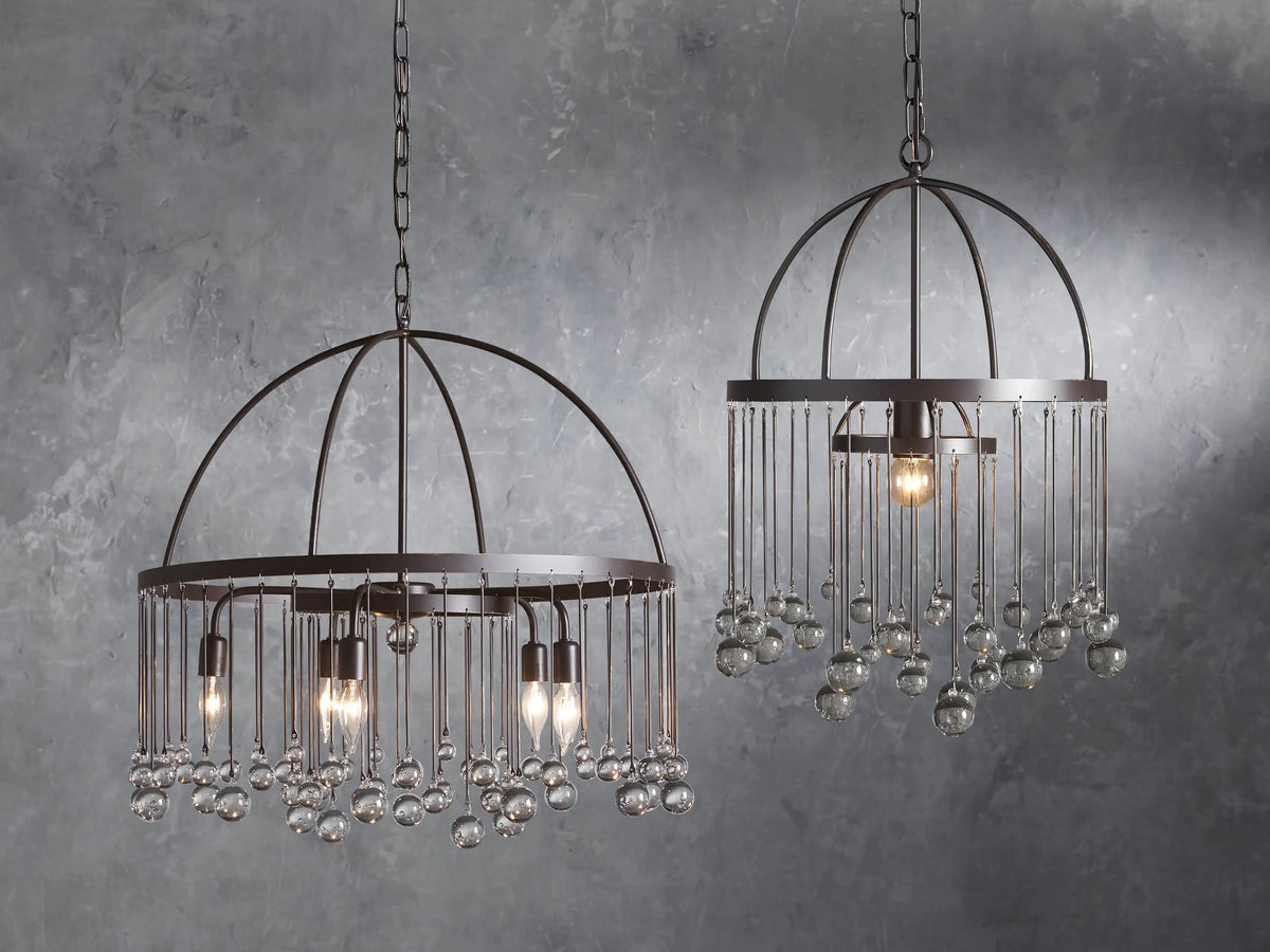 Round iron chandelier with multiple glass globes hanging, exposed bulbs, and a sleek dark frame.