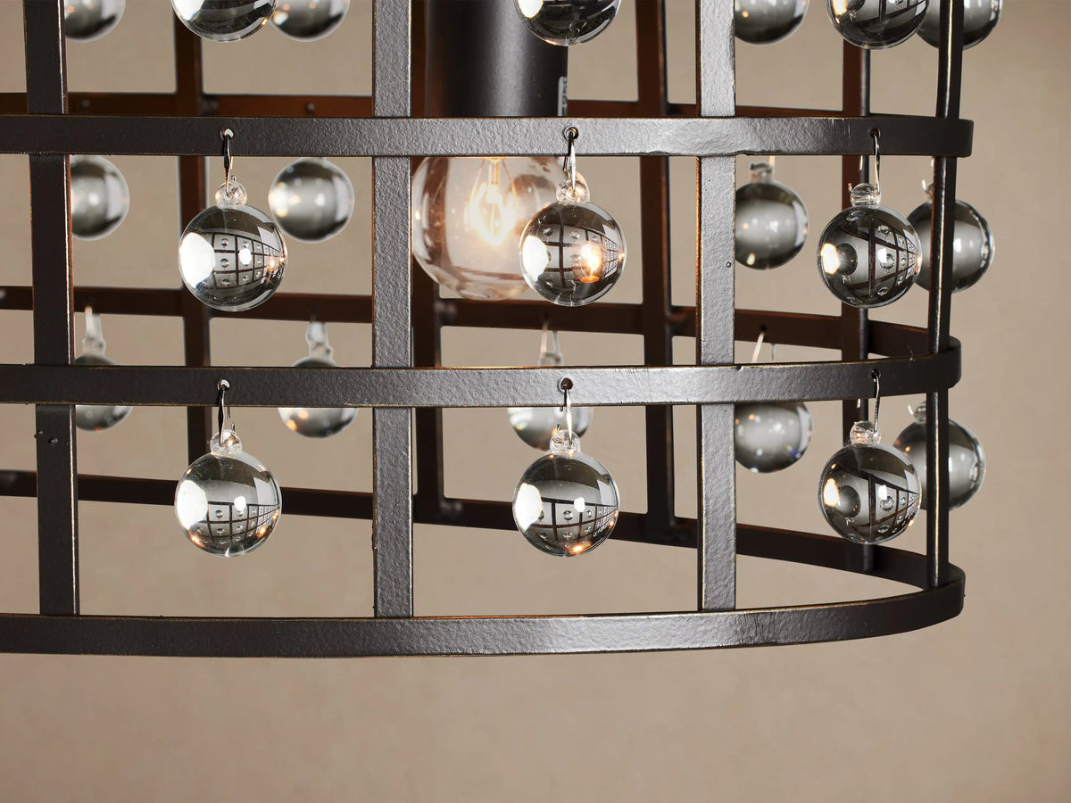 La Cage Oval Chandelier: elongated dark iron cage frame with clear crystal spheres in a grid, hanging from chains.