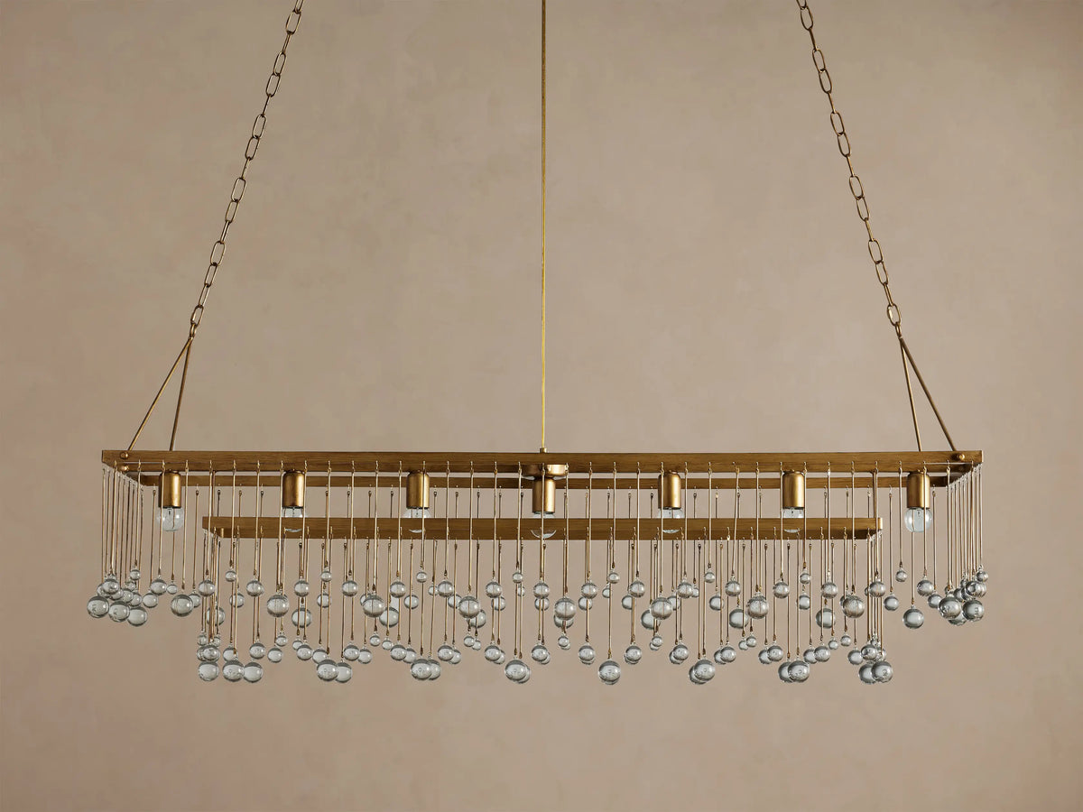 Aubrey Rectangular Chandelier, antique brass finish, adorned with rows of clear glass beads, five bulbs visible, against a wall.