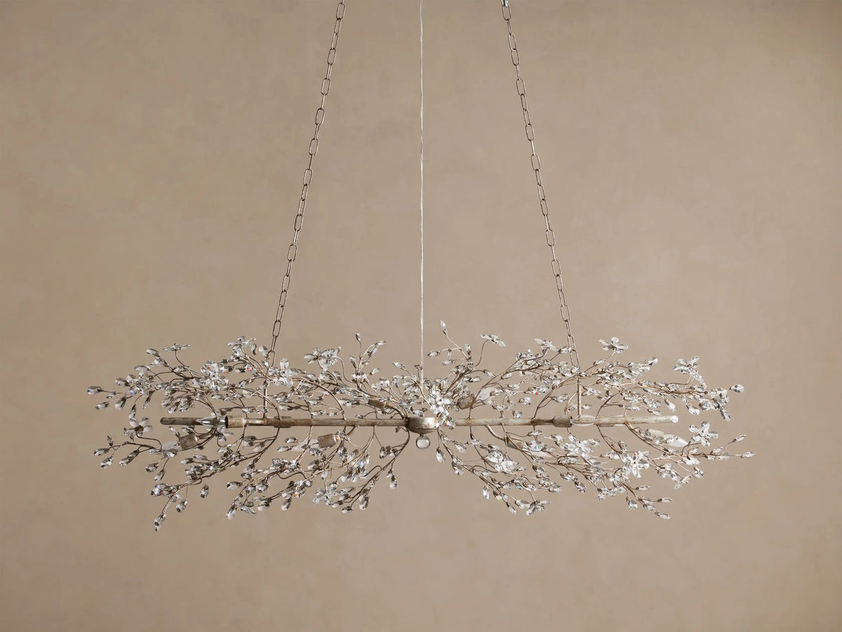 Fiore Linear Chandelier: long, antique silver frame with sparkling clear crystal flower clusters and visible bulbs, suspended by chains.